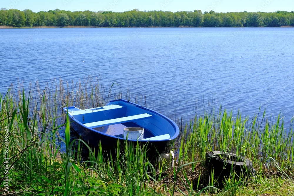 Blue wooden boat by the lake shore. Glebock Lake, Podlasie, Warmia and Masuria, Poland Blue wooden boat by the lake shore. Glebock Lake, Podlasie, Warmia and Masuria, Poland