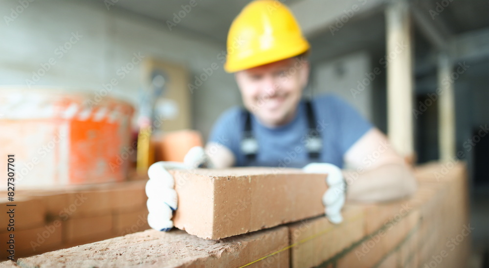 Male smiling builder puts make brickwork repair closeup. Sale of building materials concept. Male smiling builder puts make brickwork repair closeup. Sale of building materials concept.