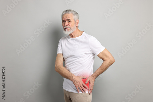 Senior man suffering from pain in hip on grey background photo