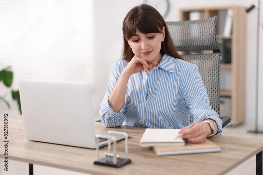 Woman taking notes during webinar at wooden table indoors Woman taking notes during webinar at wooden table indoors