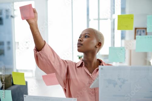 Glass, problem solving and sticky notes with business black woman in office for brainstorming or planning. Agenda, moodboard and schedule with employee in workplace for development of company vision photo