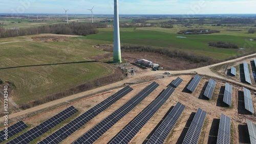 Drone footage of the solar panels rows and wind turbines in vast green field in Taurage, Lithuania photo