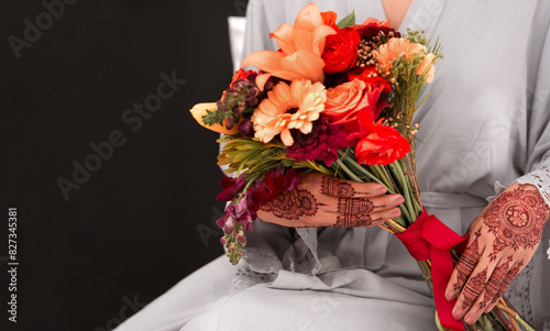 Hands, henna pattern and bouquet for wedding in studio with respect for tradition, faith and culture. Closeup, marriage and woman for walima or nikah ceremony with religious, flowers and romantic. photo