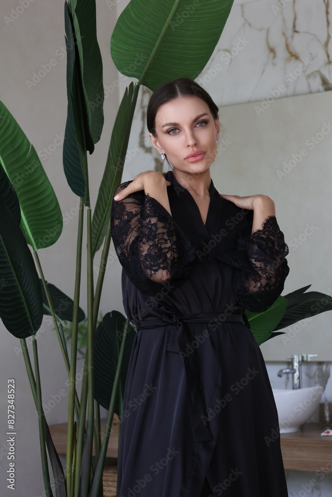 Beautiful brunette woman portrait smile. Portrait of young pretty woman in black night gown in her bathroom. Closeup, big lips. Plants, wooden table. Beautiful brunette woman portrait smile. Portrait of young pretty woman in black night gown in her bathroom. Closeup, big lips. Plants, wooden table.