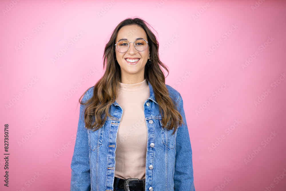 Young beautiful woman wearing denim jacket over isolated pink background with a happy face standing and smiling with a confident smile showing teeth Young beautiful woman wearing denim jacket over isolated pink background with a happy face standing and smiling with a confident smile showing teeth