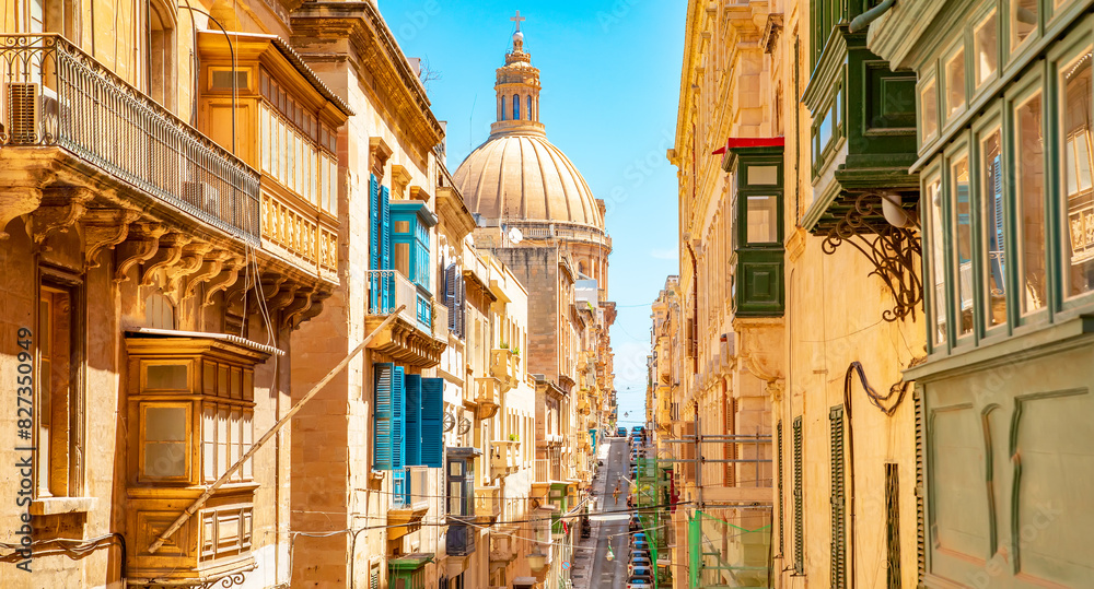 Sunny street in Valletta old town, Basilica of Our Lady of Mount Carmel on a background, Malta