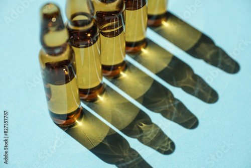 Cosmetic or medical ampoules on a blue background in a row. The ampoules cast a shadow.