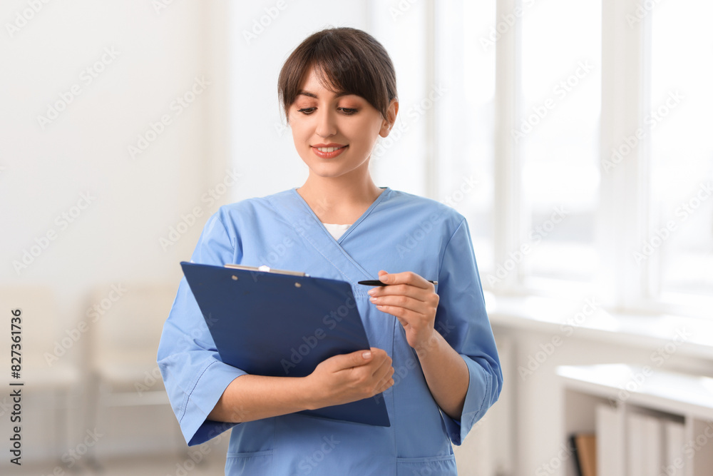 Portrait of smiling medical assistant with clipboard and pen in hospital Portrait of smiling medical assistant with clipboard and pen in hospital