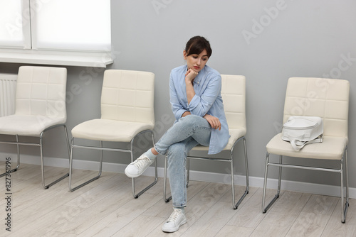 Woman sitting on chair and waiting for appointment indoors © New Africa
