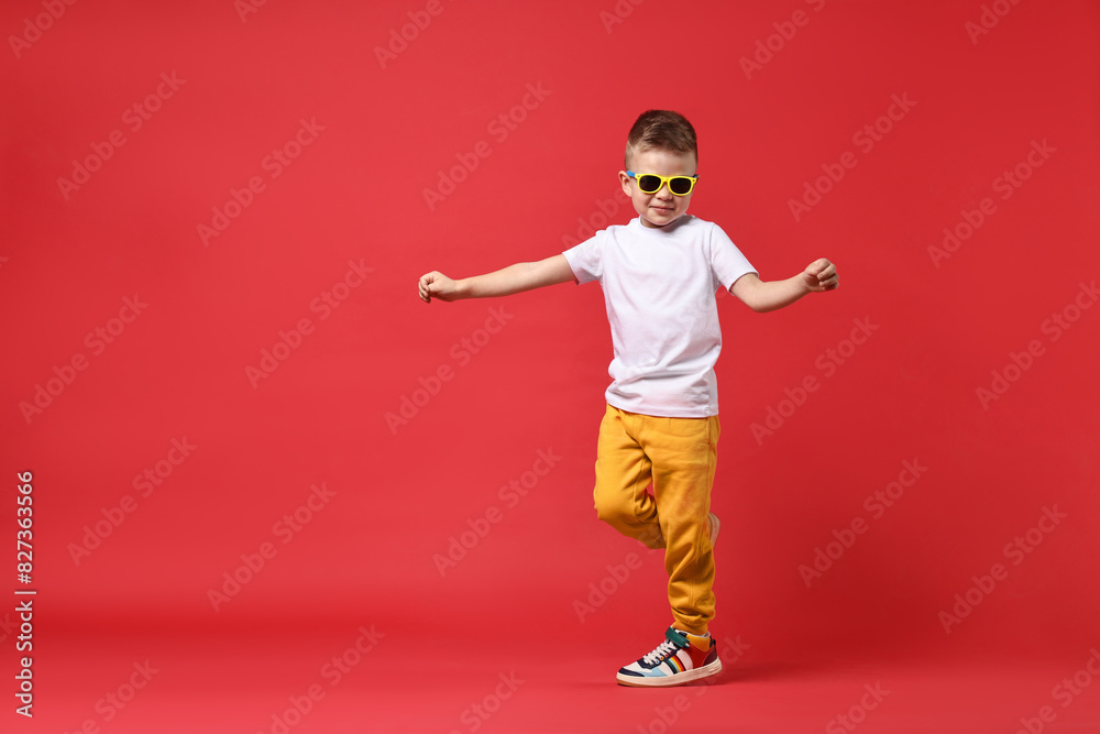 Happy little boy dancing on red background. Space for text Happy little boy dancing on red background. Space for text
