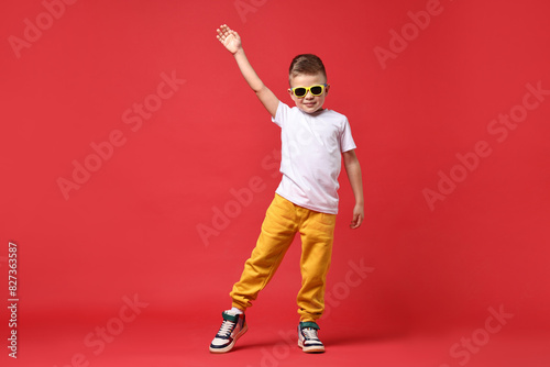 Happy little boy dancing on red background