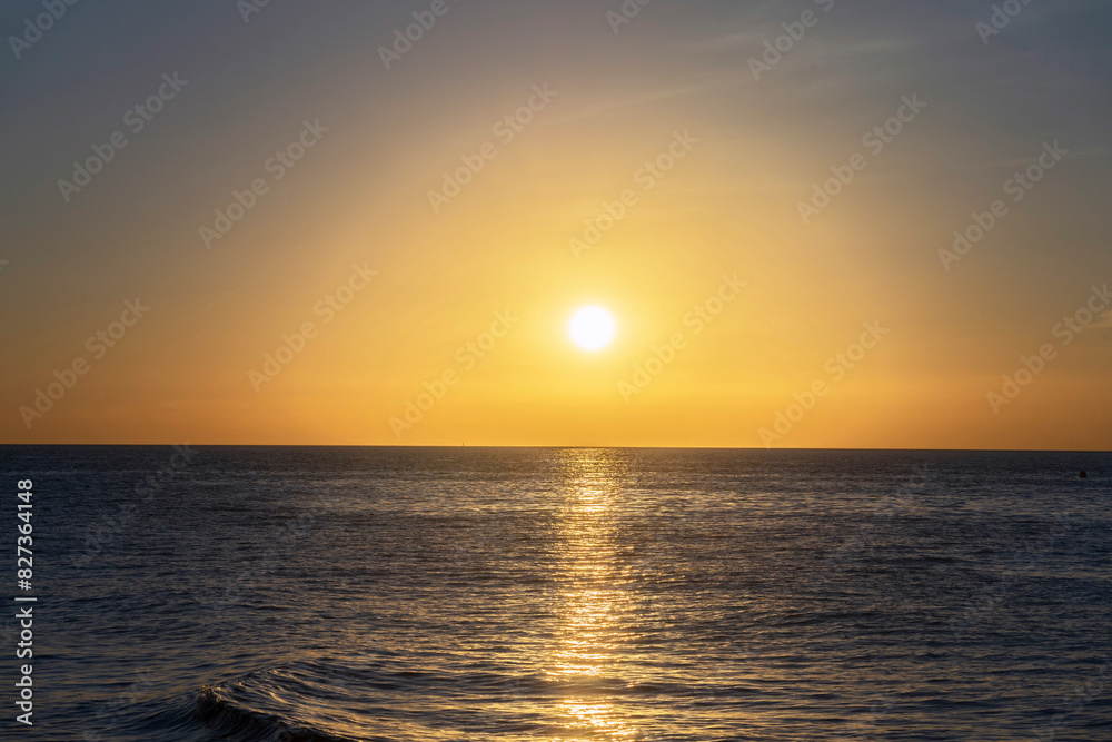 Calm sea with golden sky at sunrise. Meditation on the ocean and sky in the background.