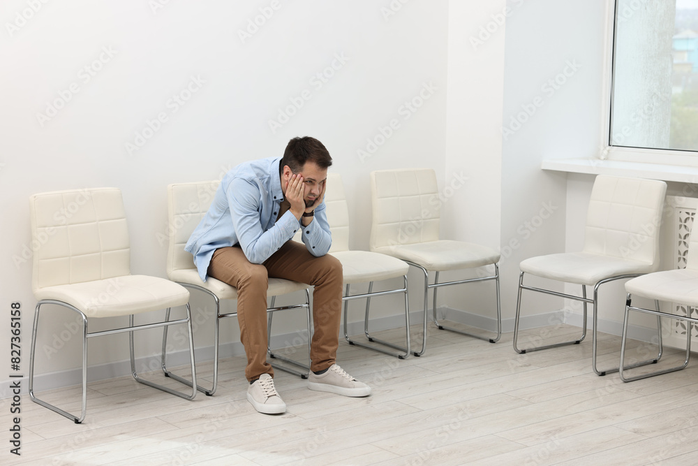 Man sitting on chair and waiting for job interview indoors Man sitting on chair and waiting for job interview indoors