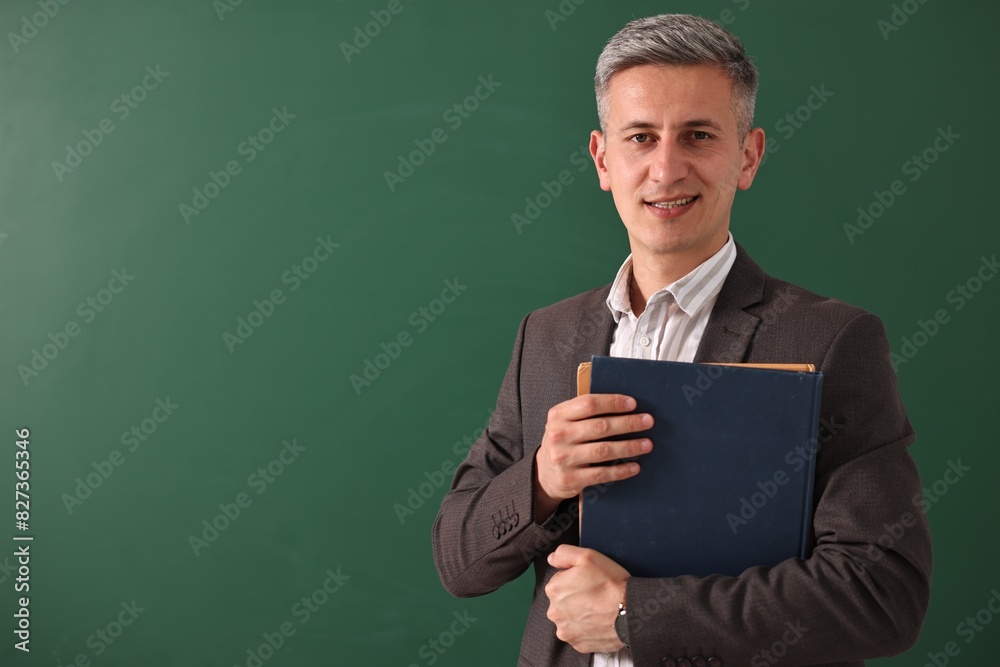 Teacher with notebooks near chalkboard, space for text Teacher with notebooks near chalkboard, space for text