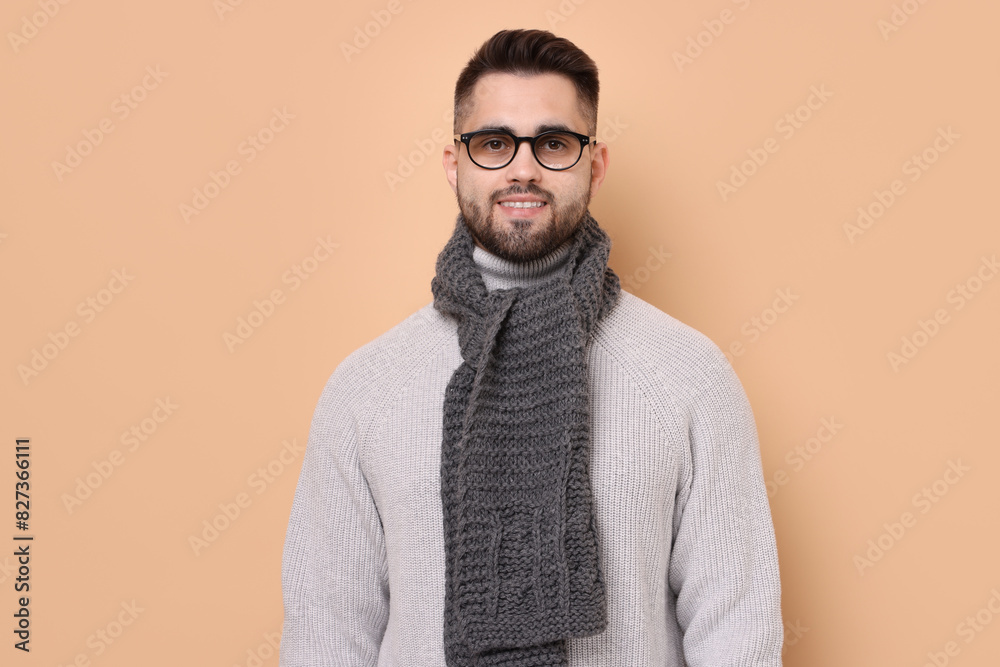 Fototapeta premium Smiling man in knitted scarf on beige background