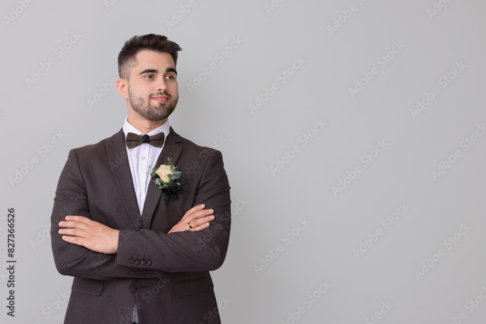 Handsome young groom with boutonniere on light grey background, space for text. Wedding accessory Handsome young groom with boutonniere on light grey background, space for text. Wedding accessory