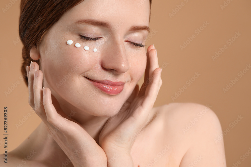 Beautiful woman with freckles and cream on her face against beige background, closeup Beautiful woman with freckles and cream on her face against beige background, closeup