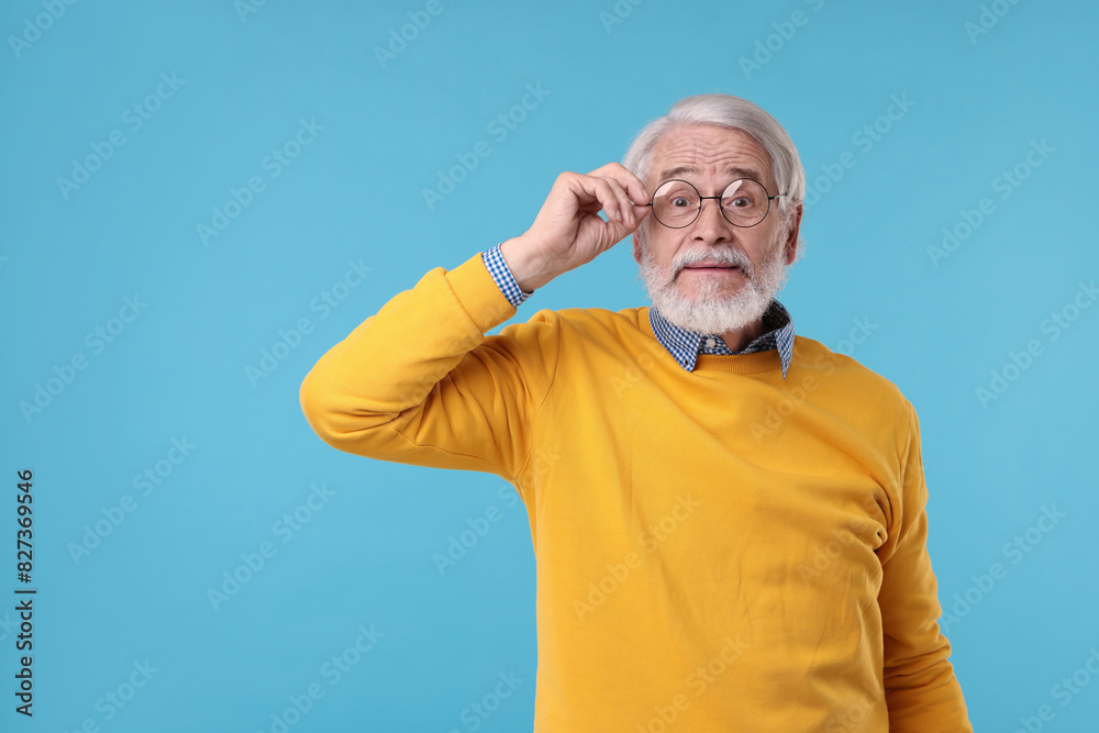 Naklejka premium Portrait of stylish grandpa with glasses on light blue background