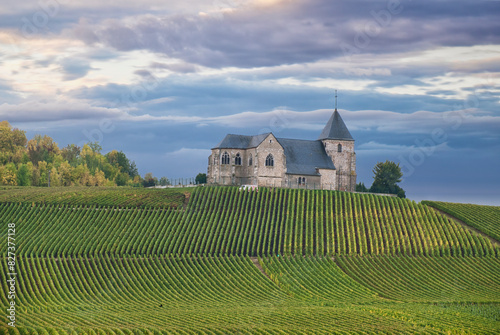 Small church Chavot in Courcourt Champagne region on a hillside next to a vineyard. The sky is cloudy and the sun is setting photo