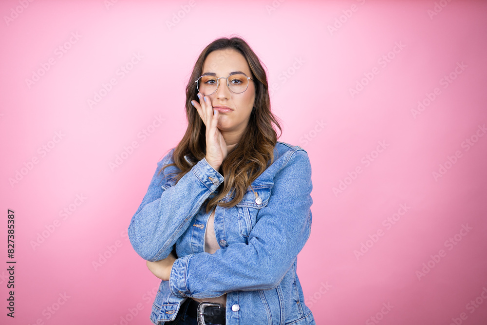 Young beautiful woman wearing denim jacket over isolated pink background thinking looking tired and bored with crossed arms Young beautiful woman wearing denim jacket over isolated pink background thinking looking tired and bored with crossed arms