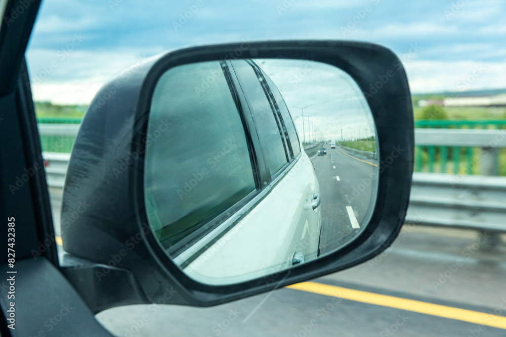 reflection of traffic flow in left side rear view mirror. road and traffic in the car rearview mirror road trip. Concept of road trip and traveling by car.