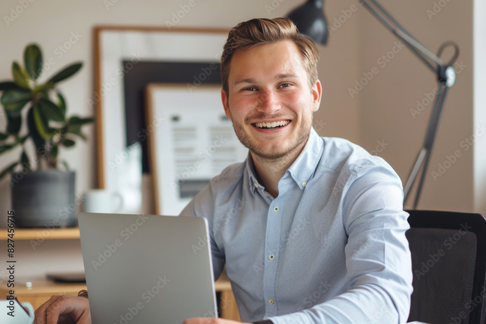 Portrait of smiling man wearing classic shirt smiling at camera while sitting at home at computer, online or remote work
