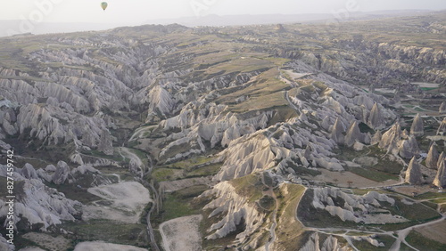 View of the rocky hills and unique landscapes of Cappadocia, Turkey, captured from a hot air balloon. The photo showcases dramatic terrain, soft morning light, and iconic geological formations,