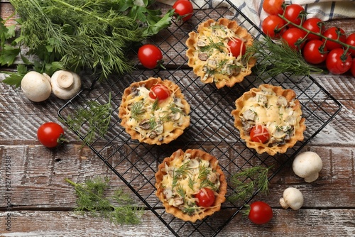 Tasty tartlets with cheese  tomatoes  mushrooms and dill among ingredients on wooden rustic table  flat lay