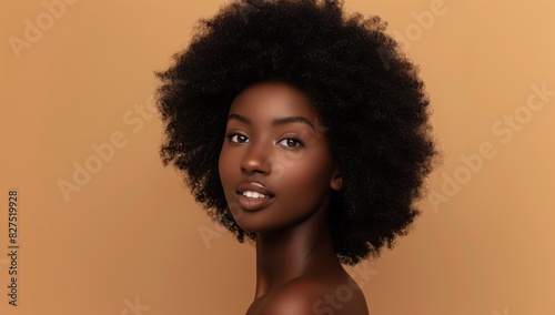 A model with a full afro poses with a confident yet serene expression, against a neutral background enhancing her natural beauty