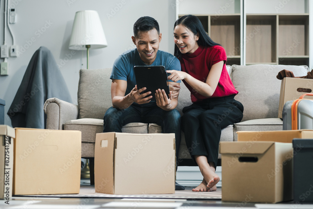 Young couple relaxing sitting on the sofa using the computer laptop around cardboard boxes, very happy moving to a new house. Young couple relaxing sitting on the sofa using the computer laptop around cardboard boxes, very happy moving to a new house.