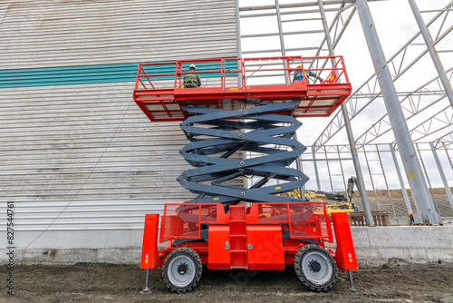 Worker is working for exterior cladding of factory on the scissor manlift in the construction side. photo