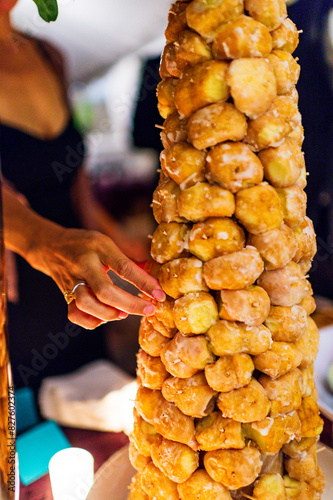 A woman's hand wearing an engagement ring selects a donut hole from a tower of donut holes at a wedding. photo