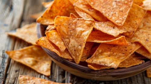 Close-up of triangular tortilla chips with spices on a wooden plate on the table. Copy space