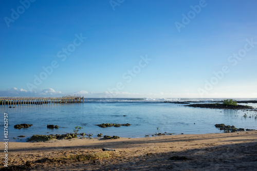 Serene view of a wooden pier extending into the calm waters at Cloud 9, Philippines. The bright blue sky and clear waters create a peaceful and inviting atmosphere. © Mirador
