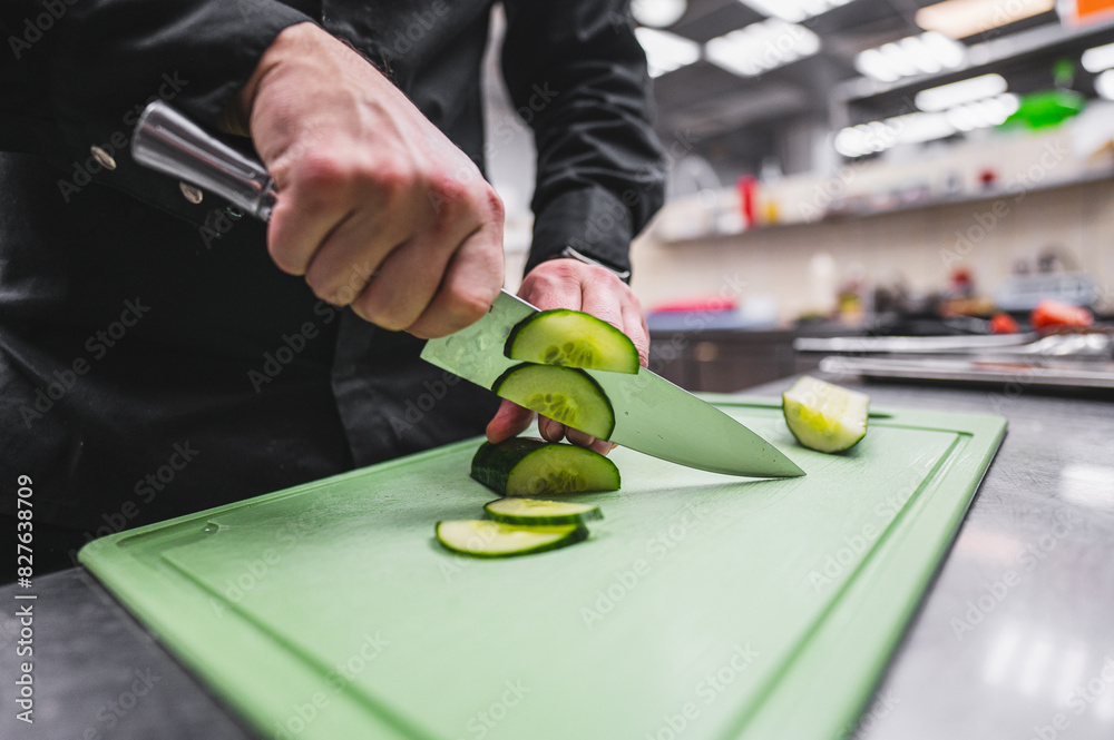 A person skillfully slices a fresh cucumber on a green cutting board using a chef’s knife A person skillfully slices a fresh cucumber on a green cutting board using a chef’s knife