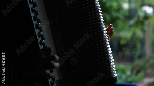 Young Boy Playing a Button Accordion on A Rainy Day, Corrientes Province, Argentina. Close Up. 4K Resolution. photo