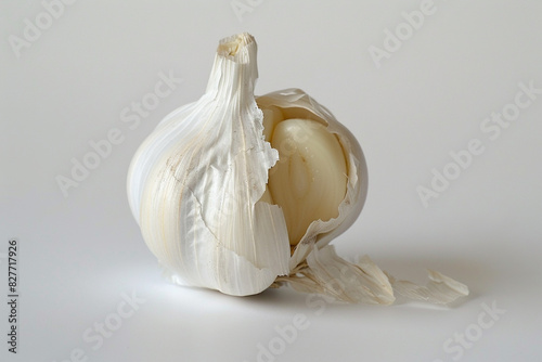 A single clove of garlic, its papery white skin intact, displayed on a white background.