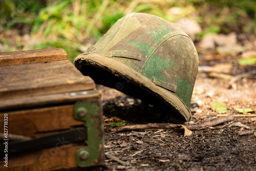 WWII german helmet on the ground. Wehrmacht m35 ( stahlhelm ) helmet in cover. Camouflage type Splinter ( splittertarnmuster ) photo