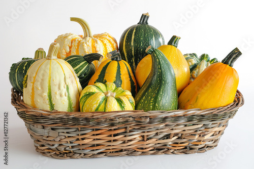 A wicker basket brimming with a variety of fresh squashes, including delicata and kabocha, showcased against a white canvas. photo