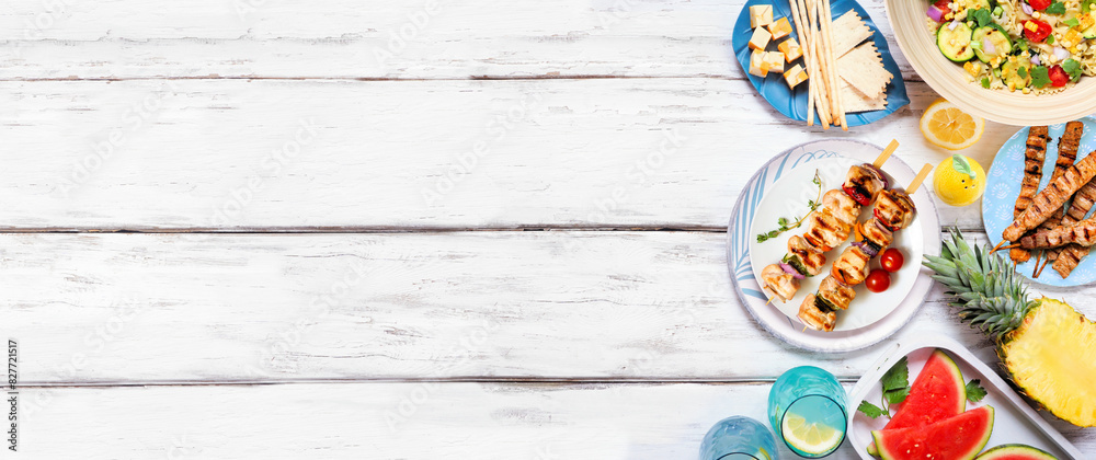 Summer food side border with  meat skewers, salad, fruit and snacks. Above view on a white wood banner background. Copy space.