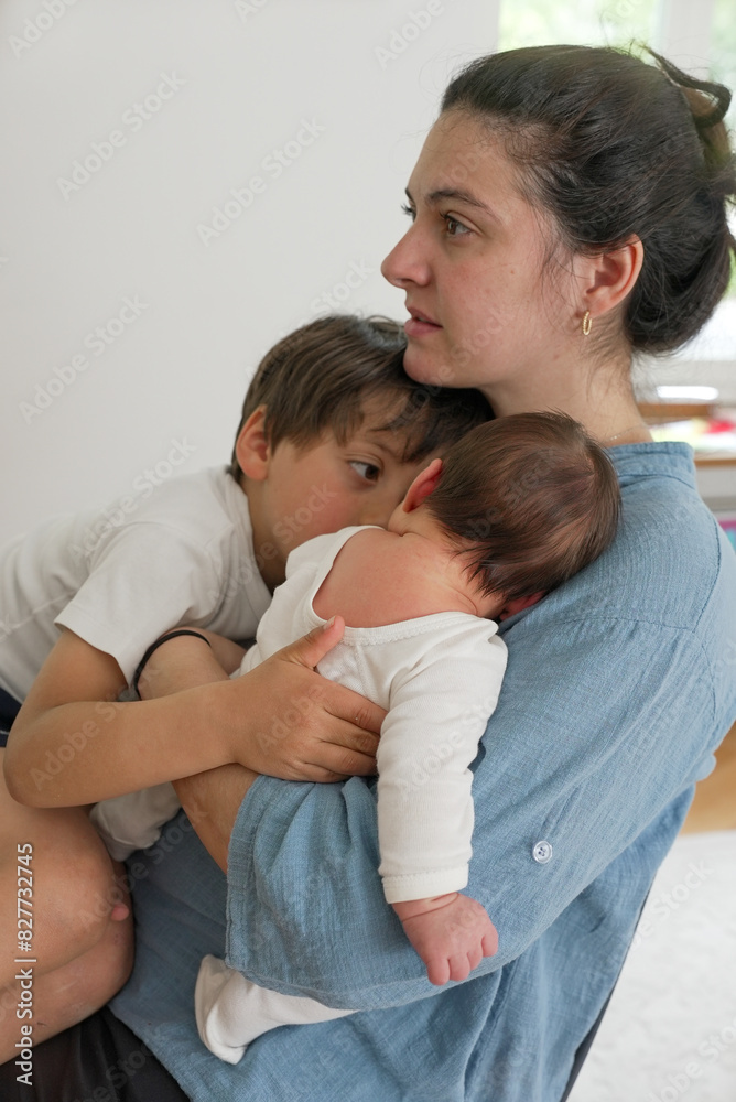 Mother with baby and young child, balancing care and attention between them, showcasing the tender moments of motherhood and the challenges of multitasking in a loving family setting Mother with baby and young child, balancing care and attention between them, showcasing the tender moments of motherhood and the challenges of multitasking in a loving family setting