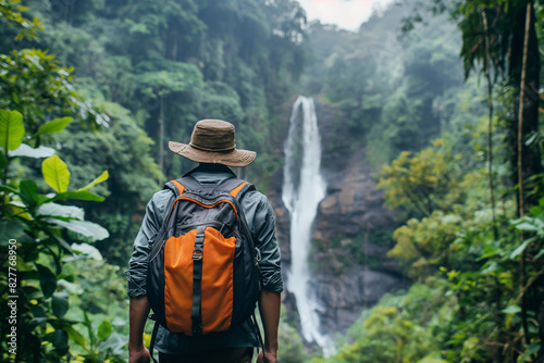 Explorer with Backpack Observing Stunning Waterfall in Dense Jungle