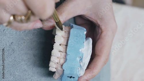 Close-up view of a dental technicians hands holding a toothbrush, focusing on manufacturing prosthesis using dental materials and tools for oral care. Vertical video. photo