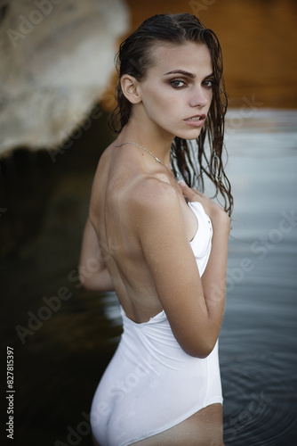 Attractive young girl in a white swimsuit in the water