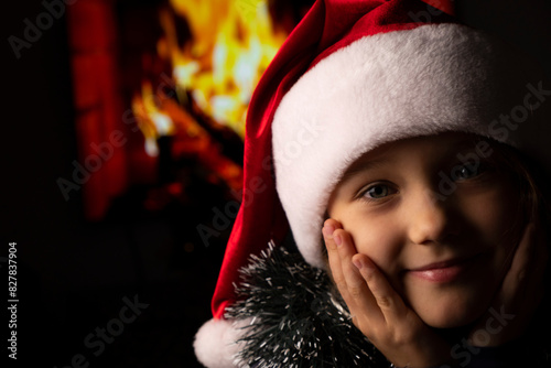 Close-up of girls in Santa's hat on background of fireplace
