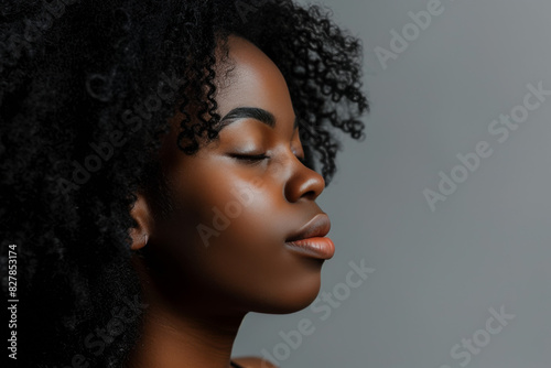 A close up of a black woman's face with her eyes closed looking to a side