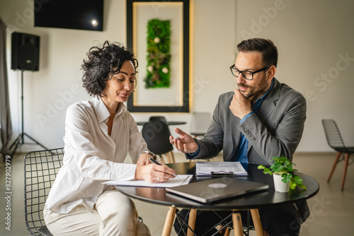 Mature woman sign insurance or contract to adult man in cafe