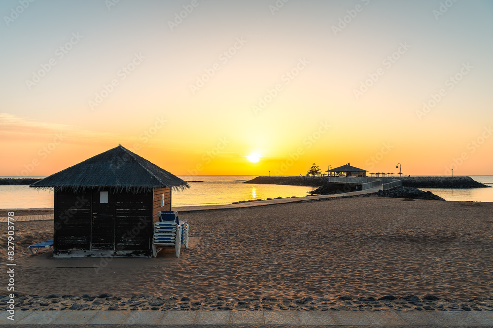 Dawn breaks over La Guirra Beach, Caleta de Fuste, casting a peaceful golden glow across the tranquil waters of Fuerteventura