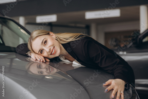 Positive young caucasian woman hugging his new car in dealership. Happy woman finally gets long-awaited car