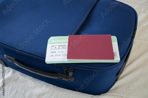 Passport and air ticket on a blue suitcase on a bed